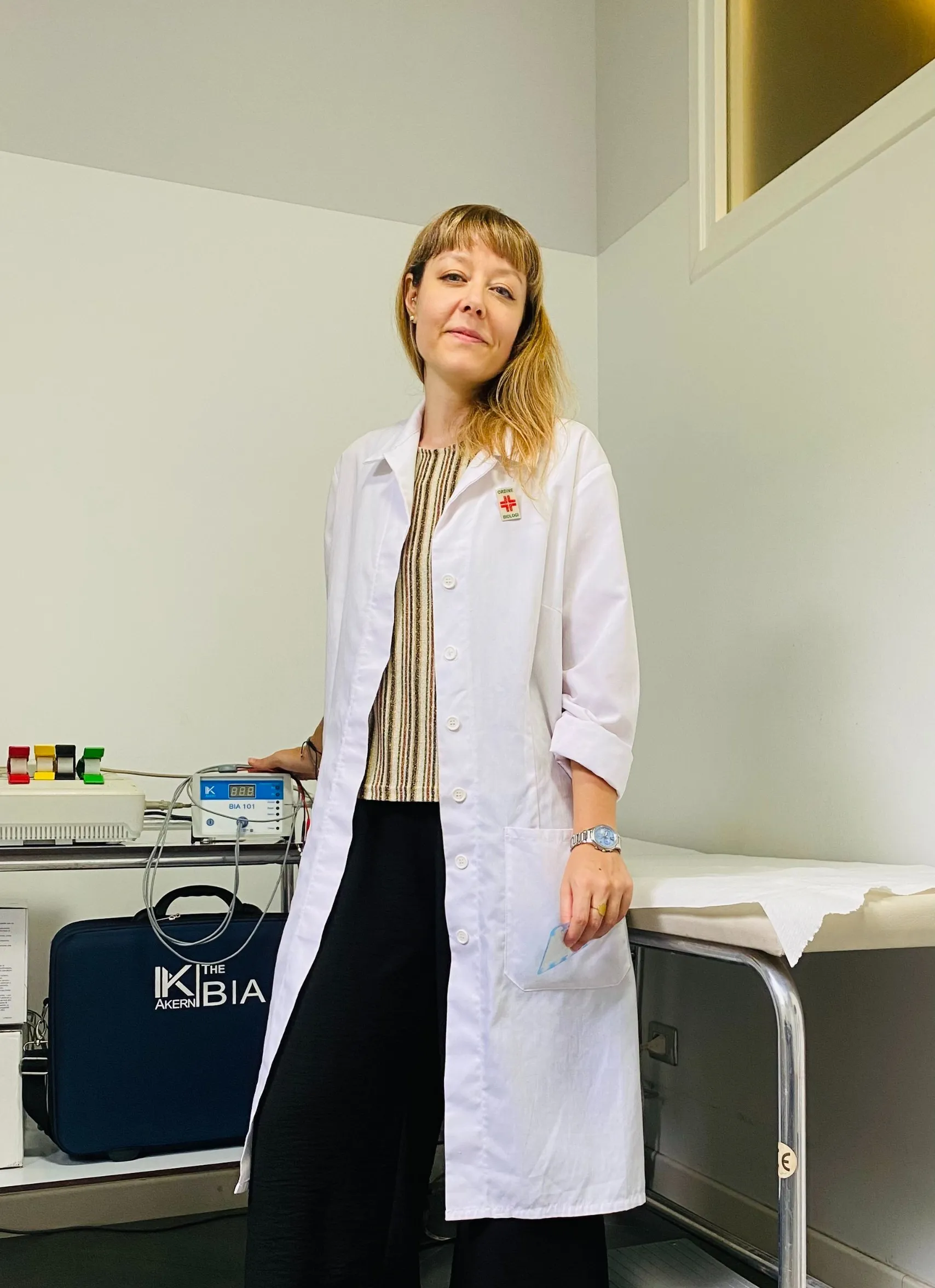 Elisa Colombo, biologa nutrizionista, in camice bianco nel suo studio accanto all'apparecchio per l'analisi impedenziometrica